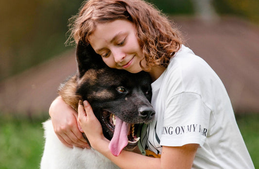Girl hugging her large dog in a calm outdoor setting, showing trust, comfort, and the emotional bond that supports canine wellness.
